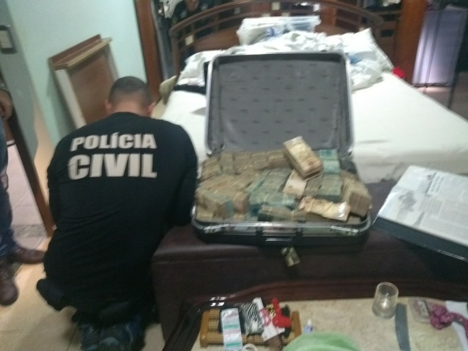 Dinheiro e pedras preciosas são encontrados pela Polícia Civil escondidos dentro de porão que era fechado no fundo falso de um guarda roupas (Foto: PC-GO)