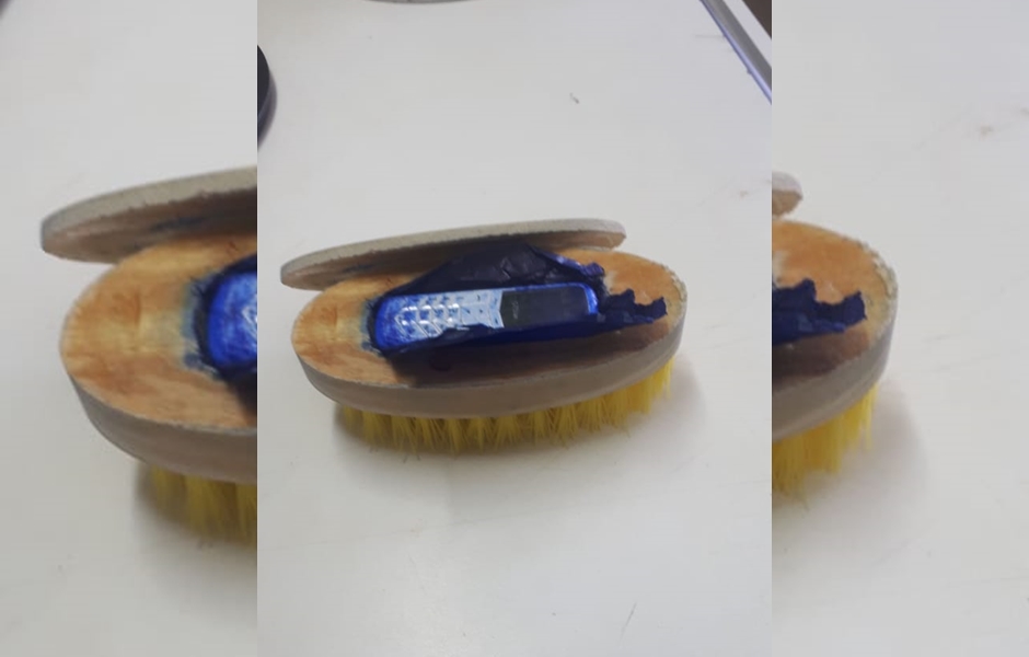 Celular estava escondido na parte da madeira da escova (Foto: Divulgação / DGAP)