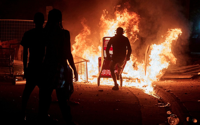 Manifestantes observam carrinhos de compra queimando perto de delegacia de polícia em Minneapolis, durante protesto pela morte de George Floyd, na noite de quarta-feira (27) — Foto: Reuters/Adam Bettcher