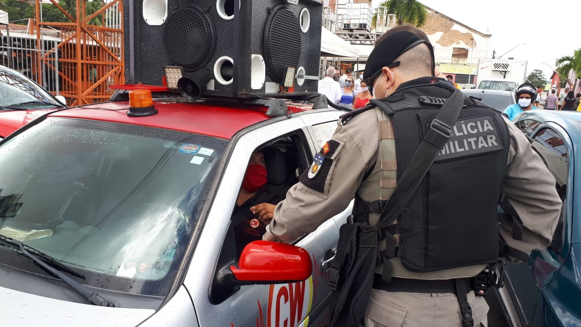 Dois homens conversam com o motorista de um carro de som