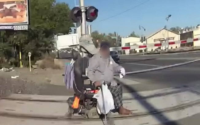 Cadeirante de 66 anos tentava cruzar uma ferrovia quando ficou preso nos trilhos de um trem. Ele foi salvo por policial, veja vídeo