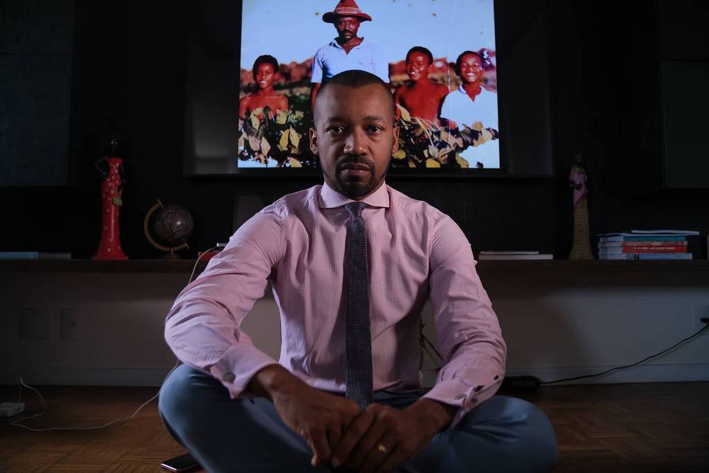 O juiz Fábio Esteves, que encabeça o movimento por igualdade racial na magistratura, posa para fotos em sua casa, em Brasília. Ao fundo, ele com os irmãos e o pai, que trabalhava na roça (Foto: Pedro Ladeira / Folhapress)