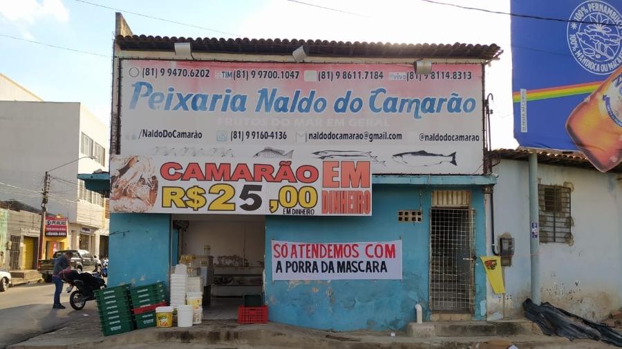 Um comerciante se irritou com clientes que adentram seu estabelecimento sem usar máscara e colocou uma faixa na porta. (Foto: arquivo pessoal)