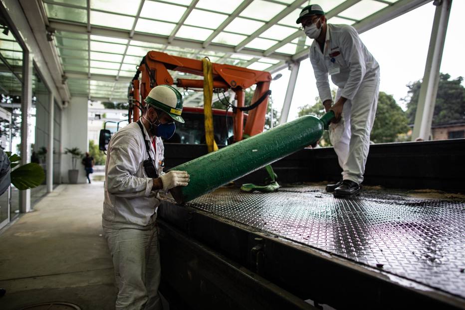 Homens carregam um cilindro de oxigênio no Hospital Universitário Getúlio Vargas, em Manaus (Foto: Raphael Alves / EFE)