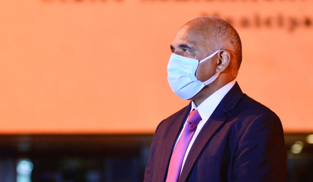 Rogério Cruz de máscara sob o fundo laranja