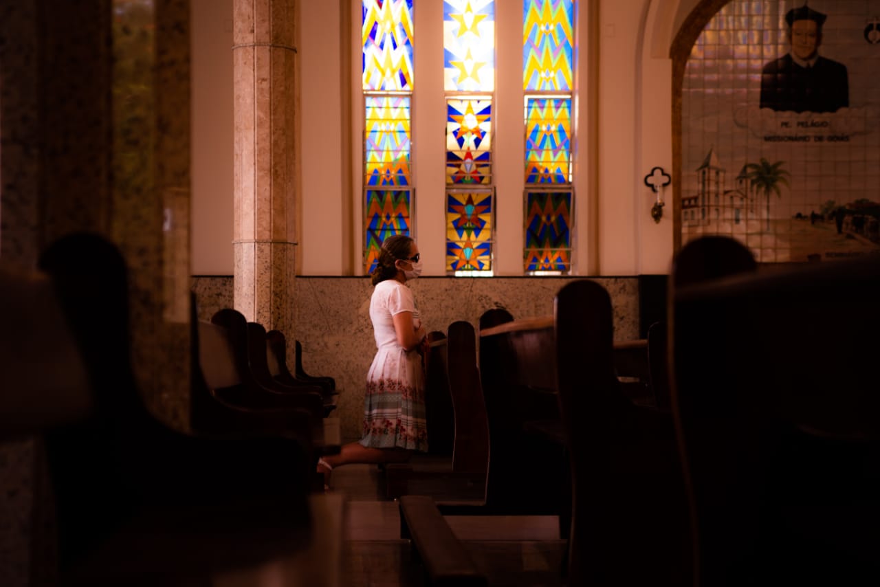 Mulher ajoelhada em igreja de Goiânia