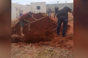Um coveiro foi flagrado de bermuda e chinelo ao sepultar uma vítima de Covid-19 em Campinorte. (Foto: reprodução/redes sociais)