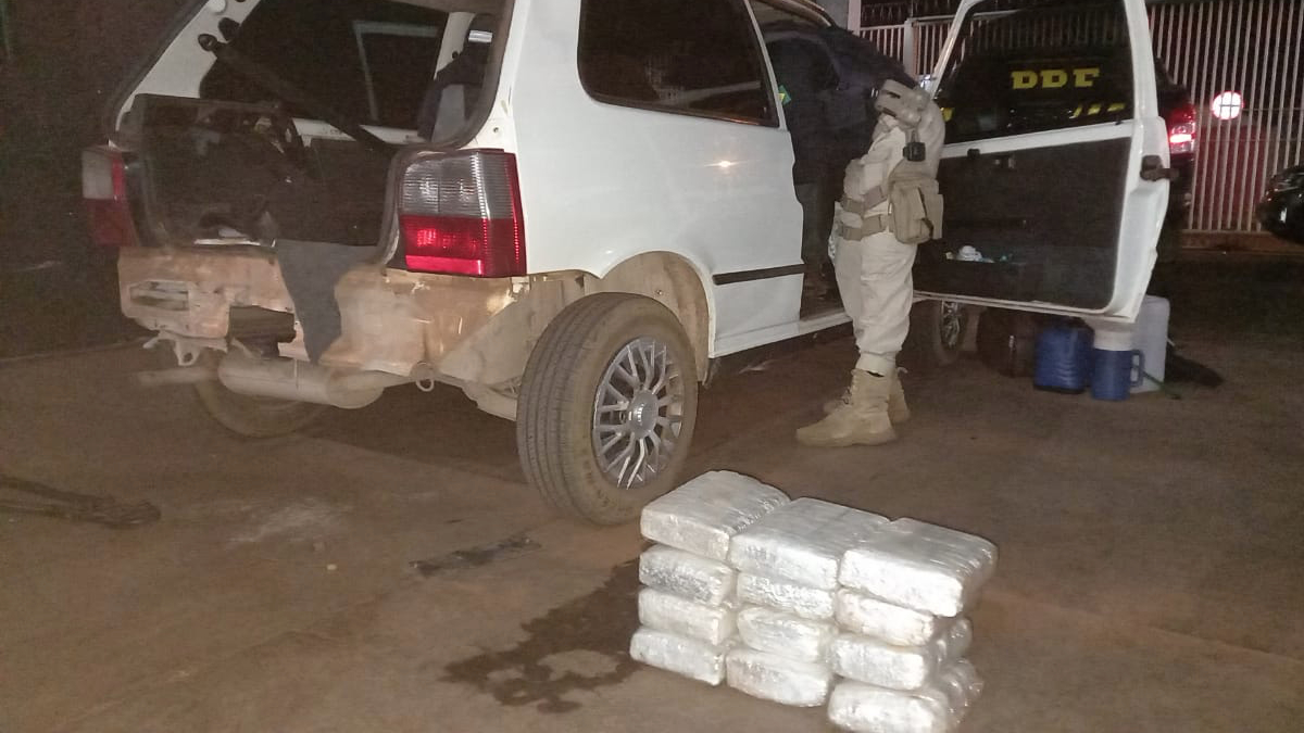 Foto mostra drogas ao lado de veículo com portas abertas, sendo vistoriado por agentes rodoviários - Casal é preso na frente do filho com 30 quilos de maconha na BR-060, em Acreúna