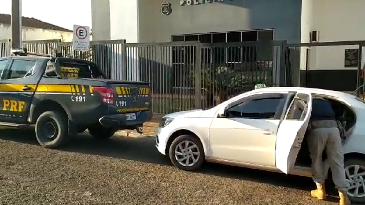 Fachada da delegacia mostra dois carros estacionados. Um deles a viatura da PRF e outro o taxi. Foto ilustra chamada: Menor é detido após pegar R$ 3 mil da avó para encontrar namorada de jogo online em Jataí