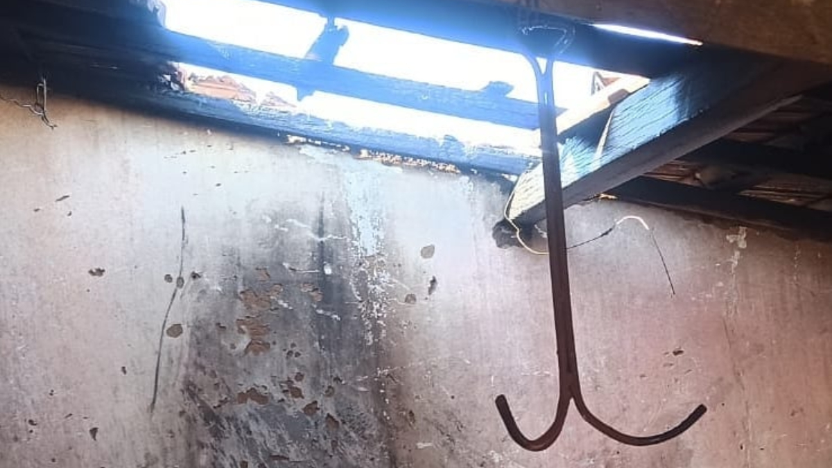 Imagem mostra teto descoberto e objeto metálico pendente. Na parede há vestígios de incêndio. Foto ilustra: Mulher tenta exterminar teias de aranha com maçarico e incendeia casa em Iporá