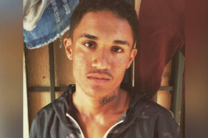 Foto mostra jovem rapaz, com curto bigode olhando para a câmera. Ele é suspeito de um assalto à ônibus na cidade de Luziânia, interior de Goiás