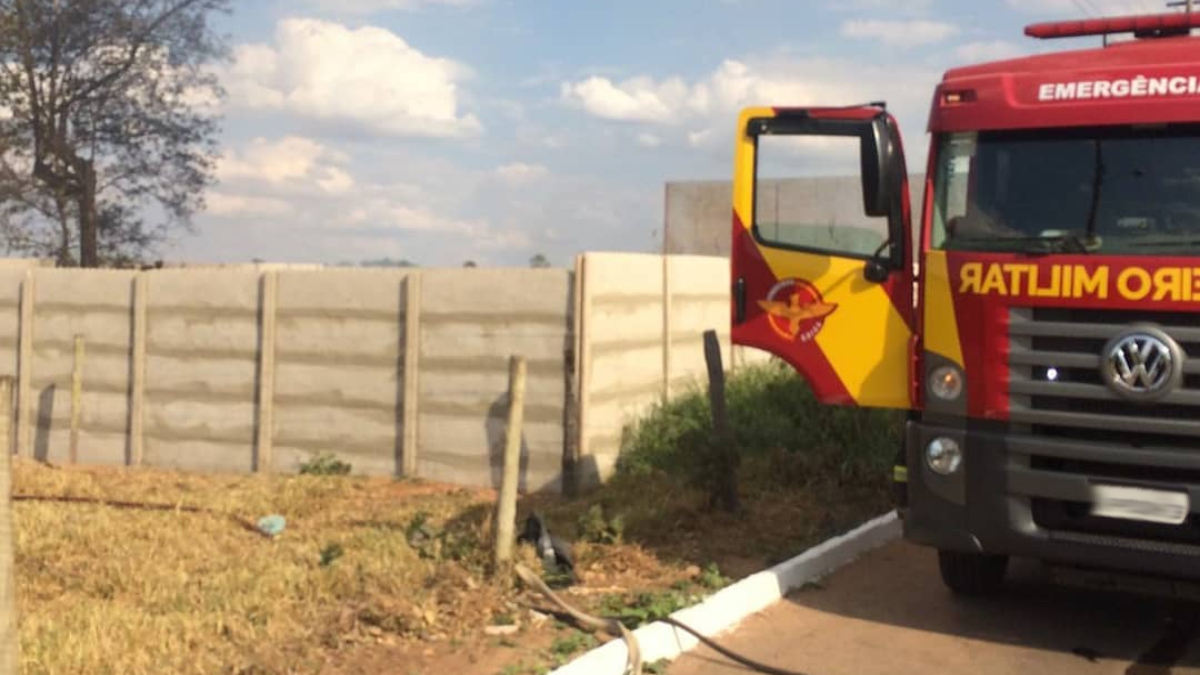 Caminhão dos bombeiros estacionado ao lado de lote onde houve incêndio. Incêndio em vegetação de lote destrói 15 carros em Goianésia