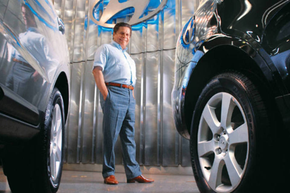 Fundador do grupo automobilístico Caoa aparece entre dois carros - ele morreu aos 77 anos