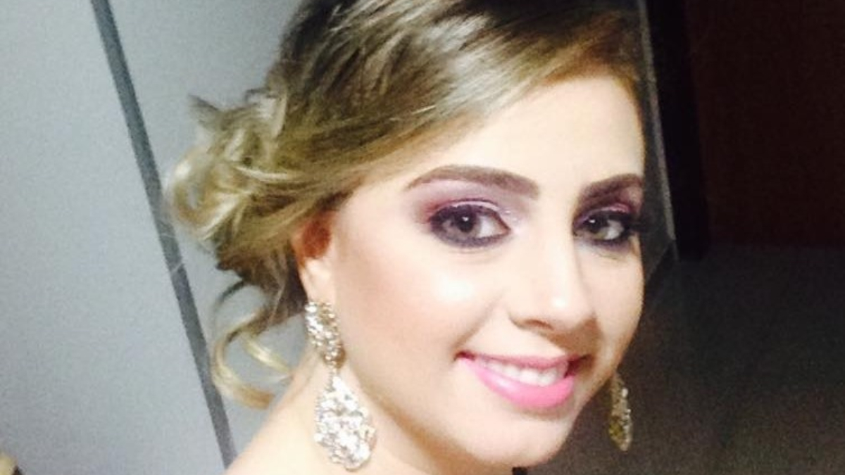 Selfie de uma das vítimas. Ela aparece sorrindo, com brincos grandes e uma maquiagem forte, de festa. O cabelo loiro está preso em um coque.