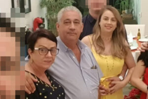 Família posa para uma selfie com outras pessoas, que foram ocultadas deste recorte. Apenas a filha sorri para a foto. O casal fica sério, como quem não percebeu o momento do registro.