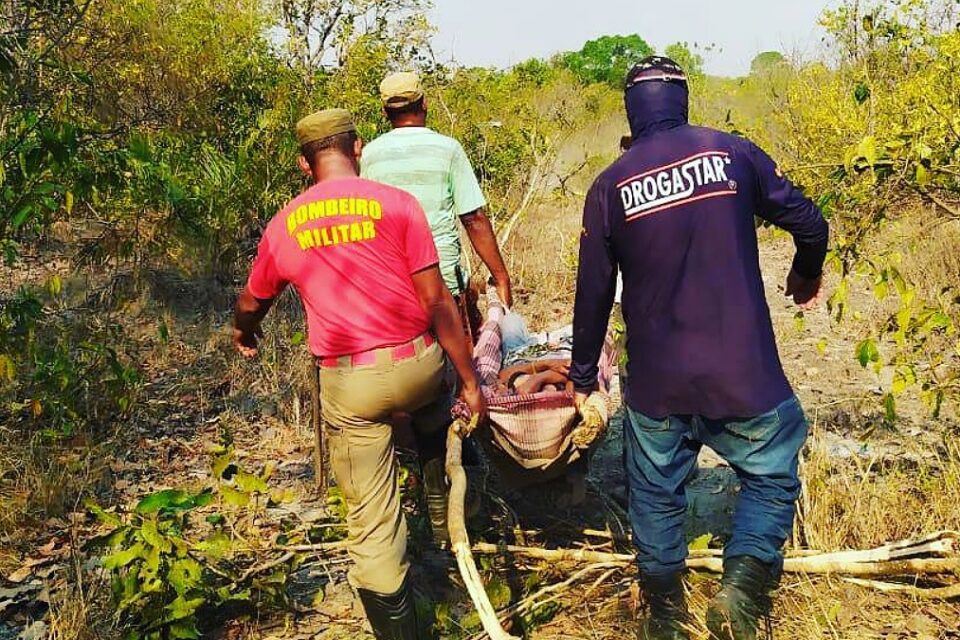Bombeiro e voluntários carregam mulher em maca improvisada no meio da mata - Mulher se perde em mata após sair para colher pequi em Mozarlândia