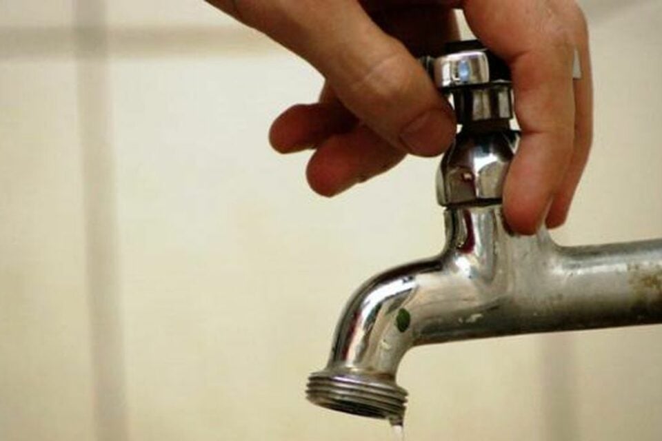 Imagem mostra uma pessoa tentando abrir uma torneira sem água