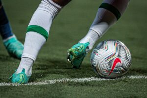 Jogador com a bola dominada no campo de futebol