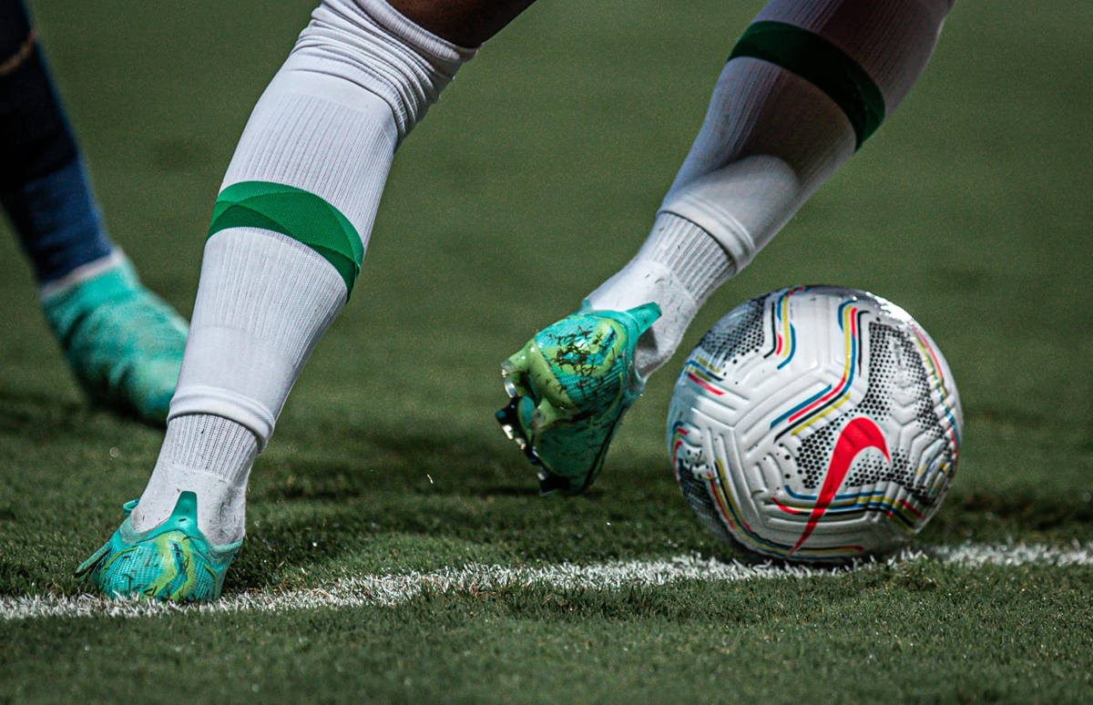 Jogador com a bola dominada no campo de futebol