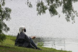 Mulher sentada no Parque Ibirapuera, em São Paulo, após flexibilização