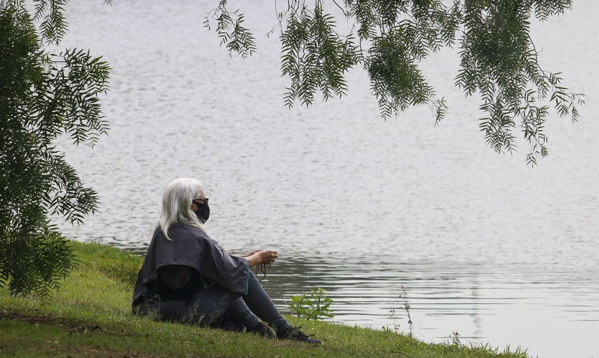 Mulher sentada no Parque Ibirapuera, em São Paulo, após flexibilização