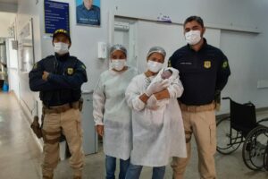 Mãe e bebê com policiais após o parto de emergência