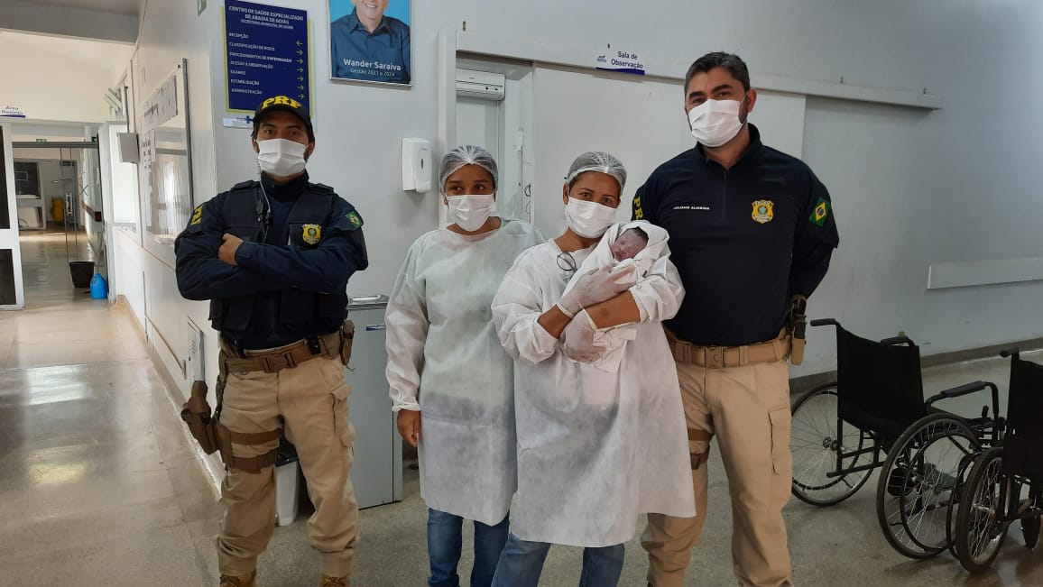 Mãe e bebê com policiais após o parto de emergência
