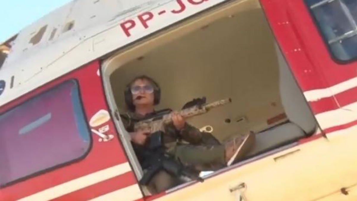 Magda Mofatto em helicóptero segurando rifle