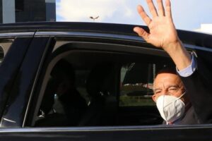 Iris Rezende de máscara acenando como um adeus de dentro de carro