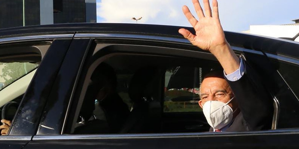 Iris Rezende de máscara acenando como um adeus de dentro de carro