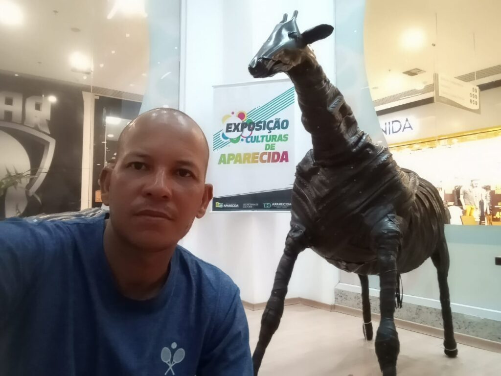 Escultor Cristiano Borges ao lado de uma girafa feita por ele (Foto: SecomAparecida)