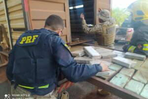 Policiais apreendendo a droga escondida no compartimento falso