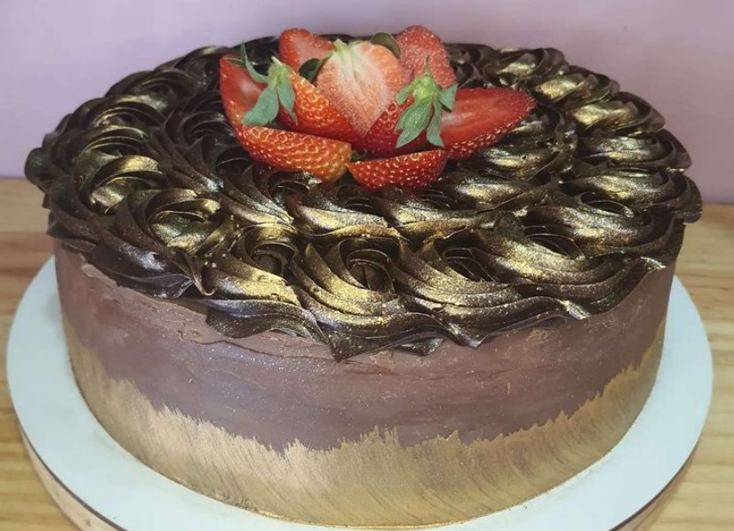Bolo bombom com rosetas de brigadeiro e morangos para decorar. Opção da Ellen Cakes, que está entre as confeitarias em Aparecida de Goiânia