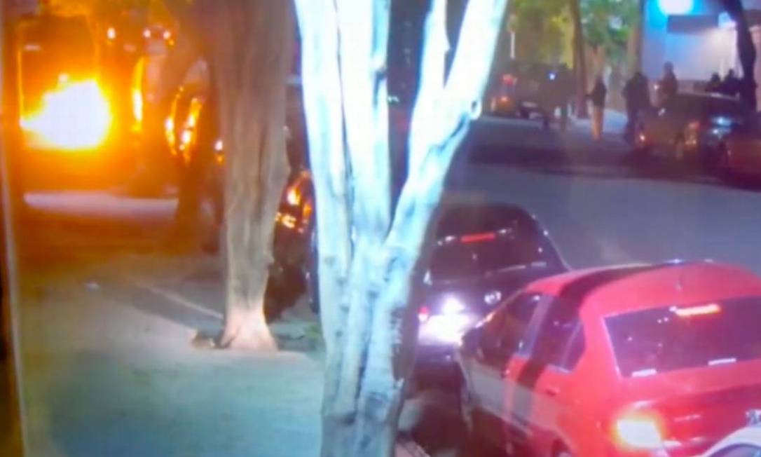 Grupo de encapuzados, à direira, ataca a entrada da sede do jornal Clarín, o maior da Argentina, com bombas incendiárias Foto: Reprodução