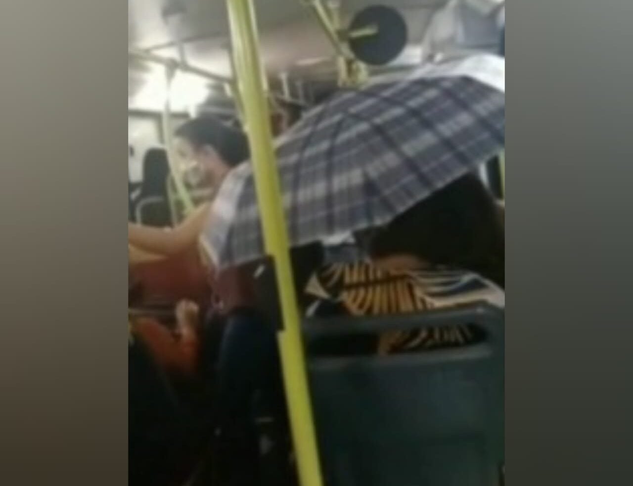 Uma mulher teve que usar um guarda-chuva para se proteger de uma goteira em um ônibus, em Goiânia, na última terça-feira (30). (Foto: reprodução/TV Anhanguera)