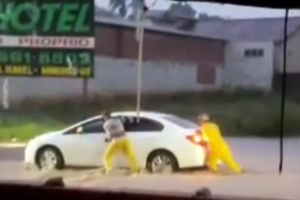 Garis empurram carro que parou em rua alagada de Mineiros