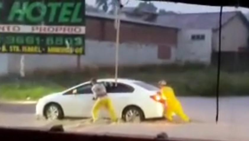 Garis empurram carro que parou em rua alagada de Mineiros