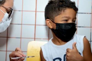 Criança faz o gesto de positivo ao receber vacina em Aparecida de Goiânia (Mais de 39% das crianças se vacinaram contra a Covid-19 nas escolas em Aparecida)