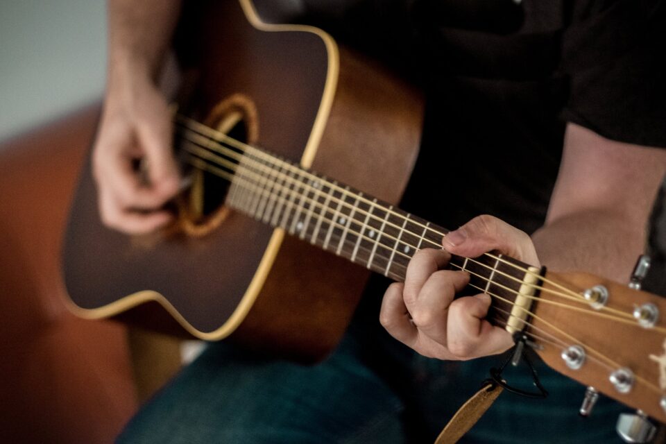 Foto de um violonista fazendo acorde no instrumento
