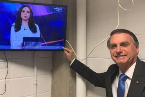 Candidato à reeleição, ele foi o entrevistado no Jornal Nacional. Bolsonaro posa ao lado de TV ligada no SBT e diz: 'Bastidores Globo'