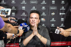 Adson Batista com as mãos juntas em coletiva