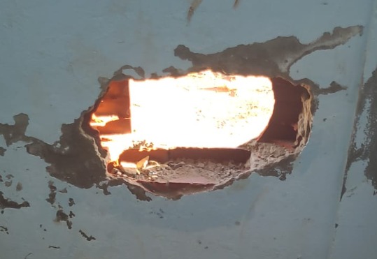 Buraco aberto por detentos na cela permitiu que eles acessassem o pátio e pulassem o muro do Presídio de Trindade (Foto: DGAP)