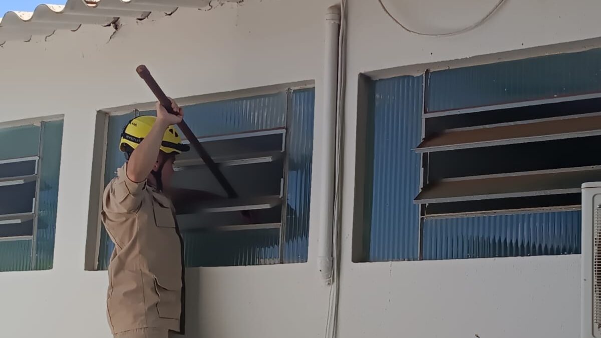 Um dos bombeiros militares resgata a criança que ficou presa no banheiro.