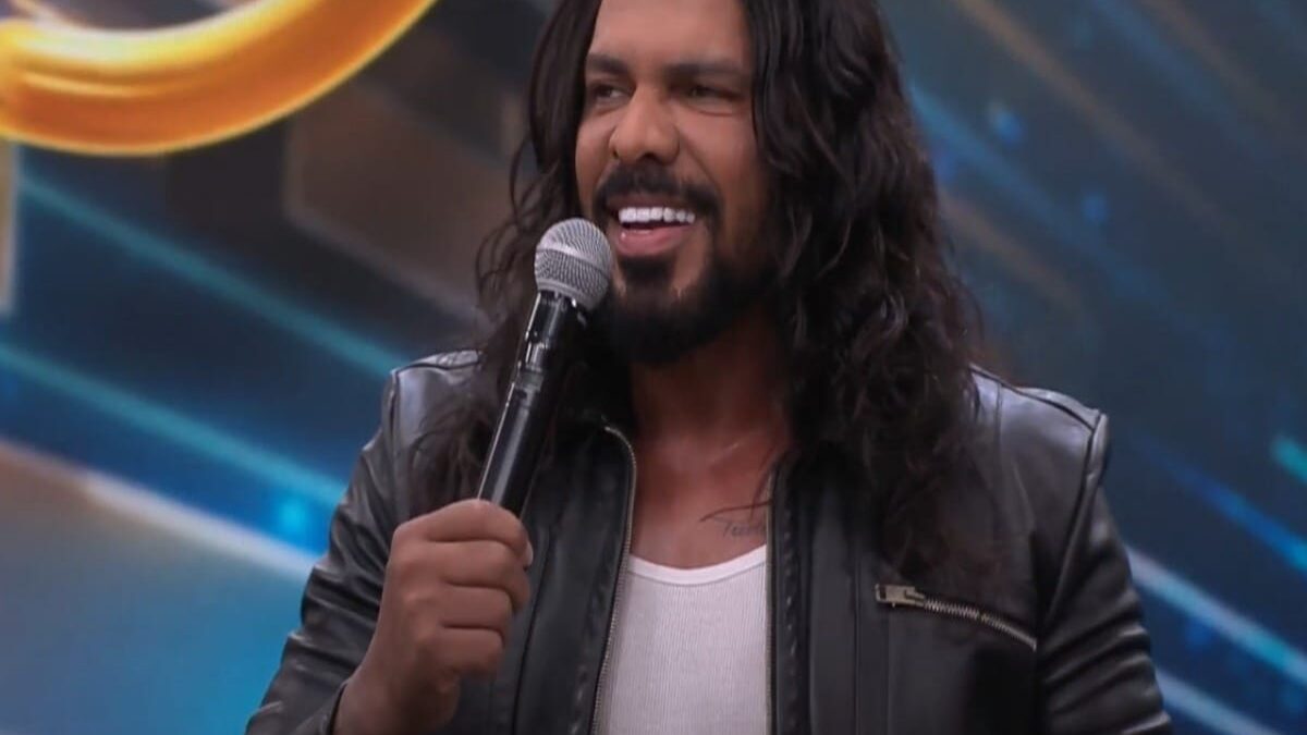 Cantor sertanejo Thales Lessa, acusado de importunação sexual, aparece sorrindo e segurando um microfone.