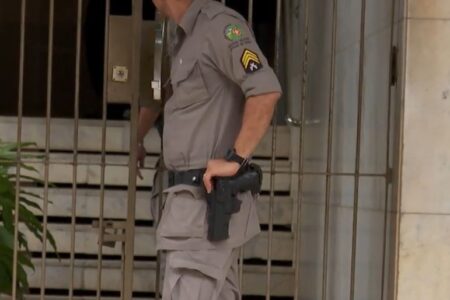 PM não identificado apoia braço sobre coldre com arma de fogo diante da portaria do prédio onde agente da SMM foi morto após fazer namorada refém, em Goiânia (Foto: PM)