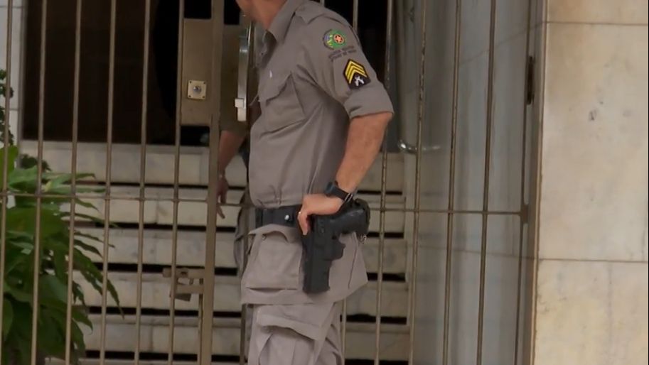 PM não identificado apoia braço sobre coldre com arma de fogo diante da portaria do prédio onde agente da SMM foi morto após fazer namorada refém, em Goiânia (Foto: PM)