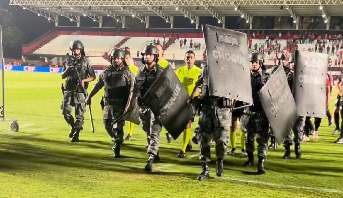 Árbitro sendo escoltado pela polícia para deixar o gramado