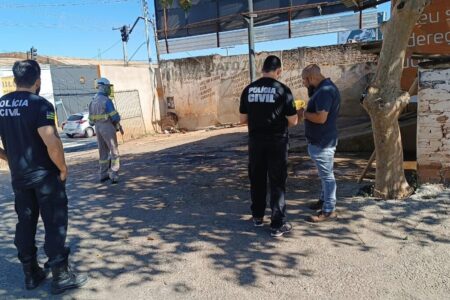 Imagem colorida mostra um agente da Polícia Civil conversando com um homem dentro de um laa jato