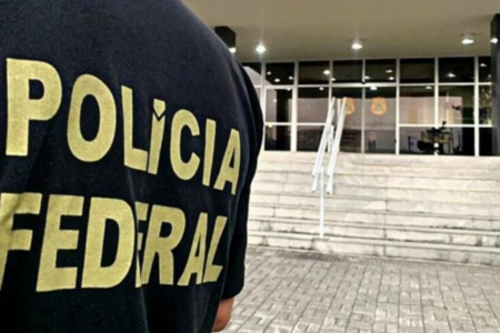 Imagem colorida mostra um agente da Polícia Federal de costas.