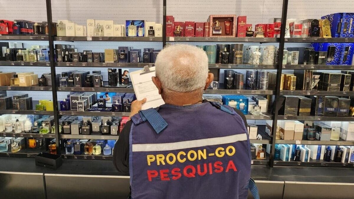 Imagem colorida mostra um homem com cabelos brancos virado de costas usando um colete azul